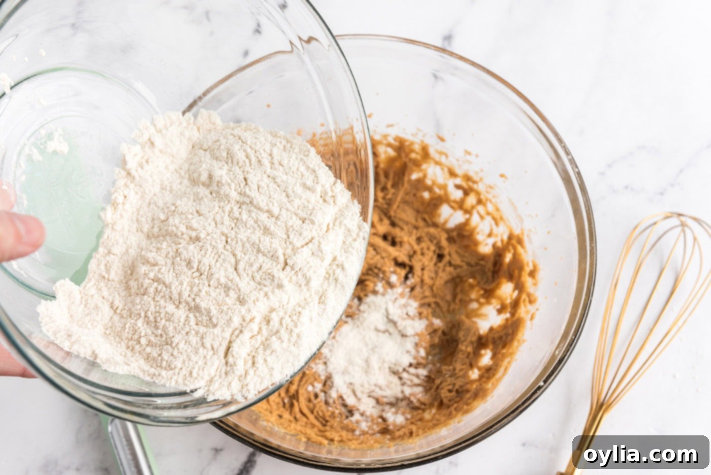 adding dry ingredients to wet ingredients for peanut butter cookie dough