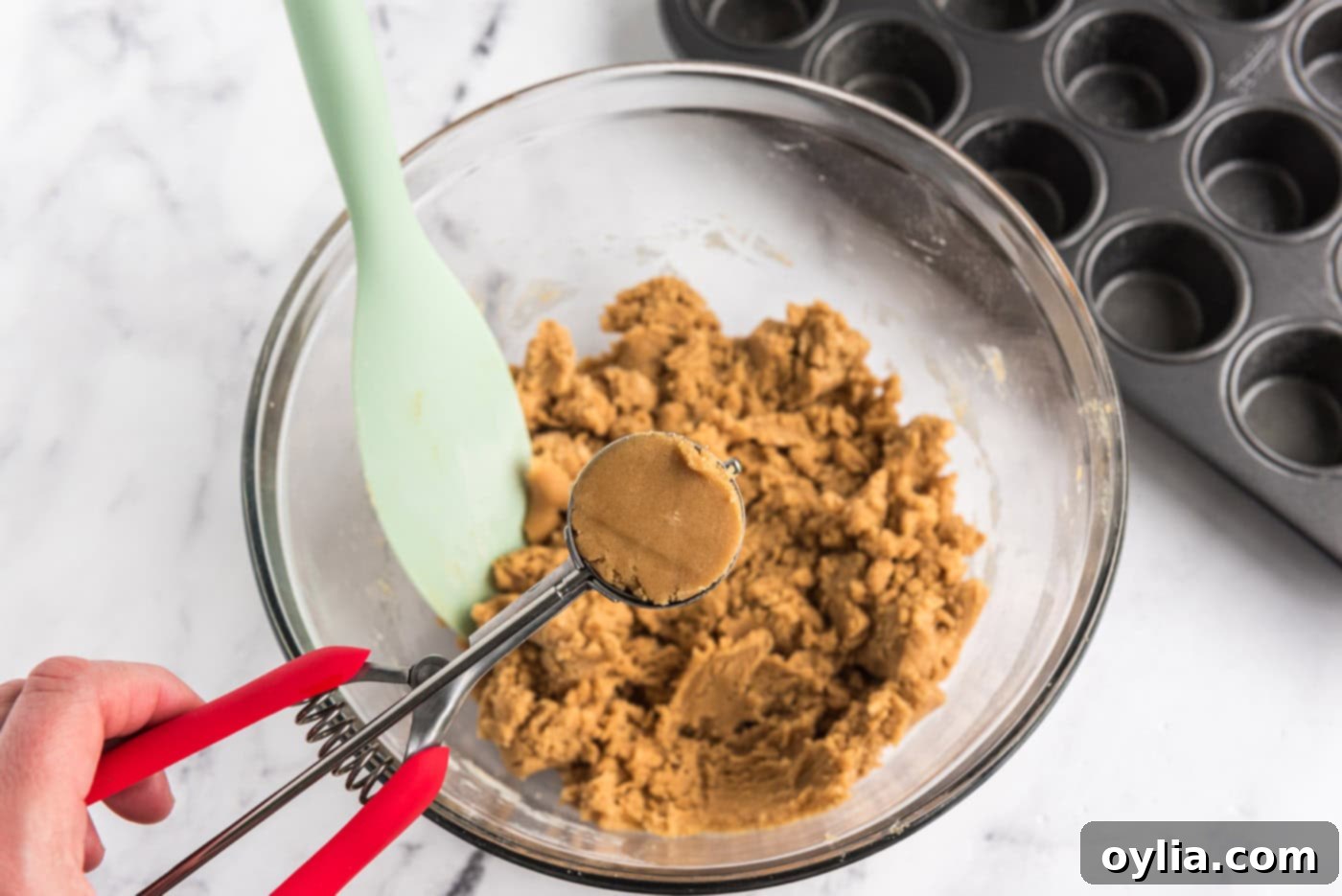 scooping peanut butter cookie dough from bowl with a cookie scoop