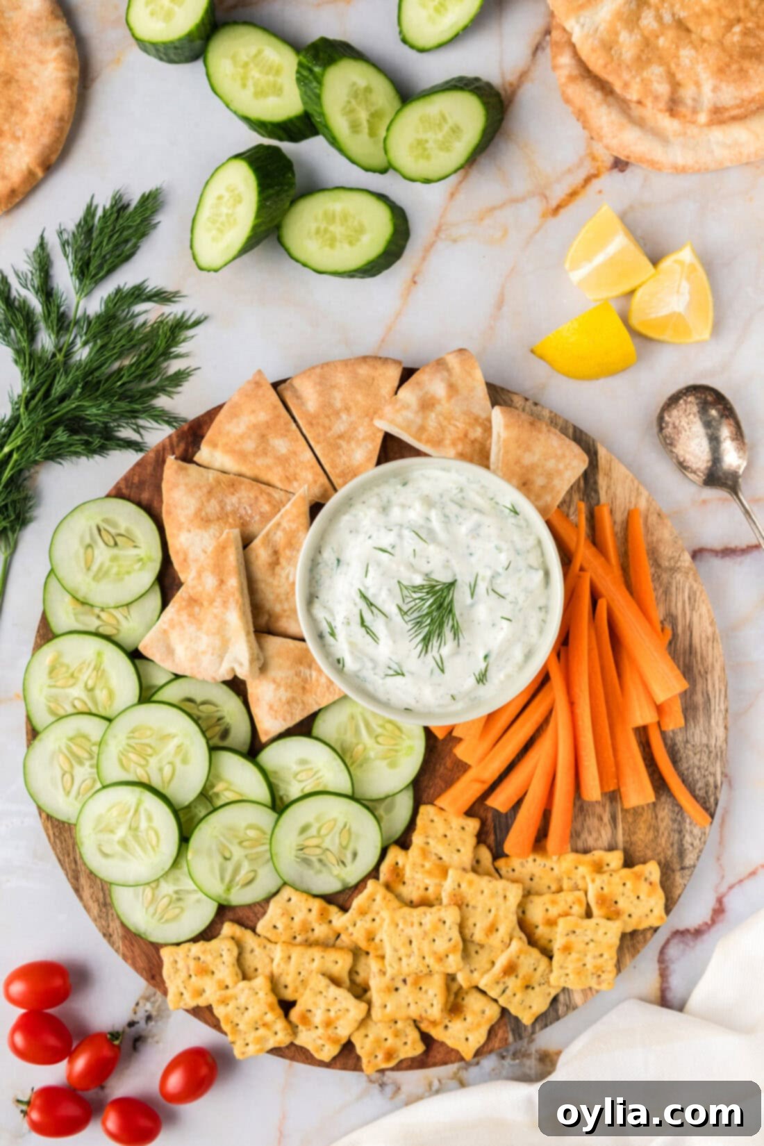 Refreshing Greek Tzatziki Dip 2 Tzatziki Sauce in a bowl on a platter with pita bread, crackers, carrots and cucumbers