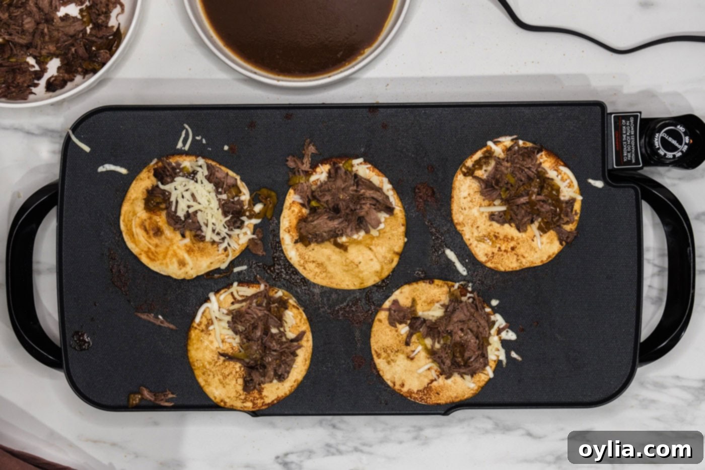 Tender shredded Mississippi pot roast layered over melted cheese on an au jus soaked tortilla