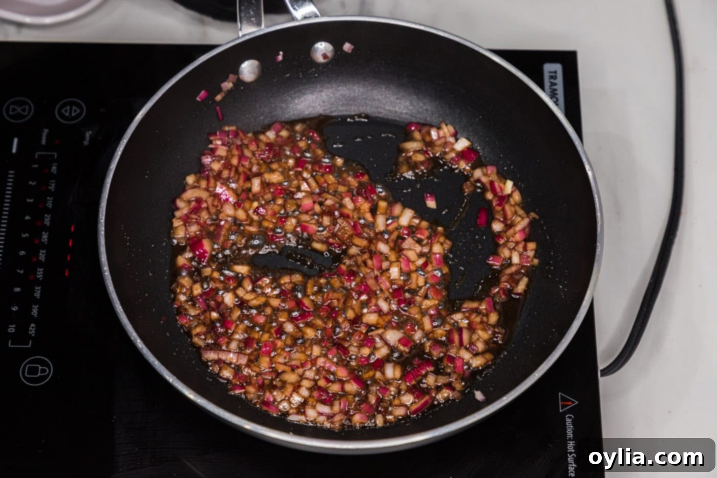 red onion sauteeing in olive oil in a skillet with liquid smoke and worcestershire sauce