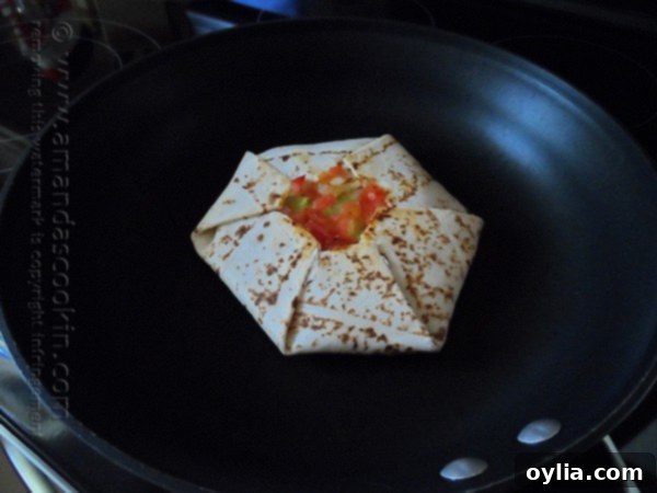 A homemade Crunchwrap Supreme being flipped in a skillet to brown the second side.