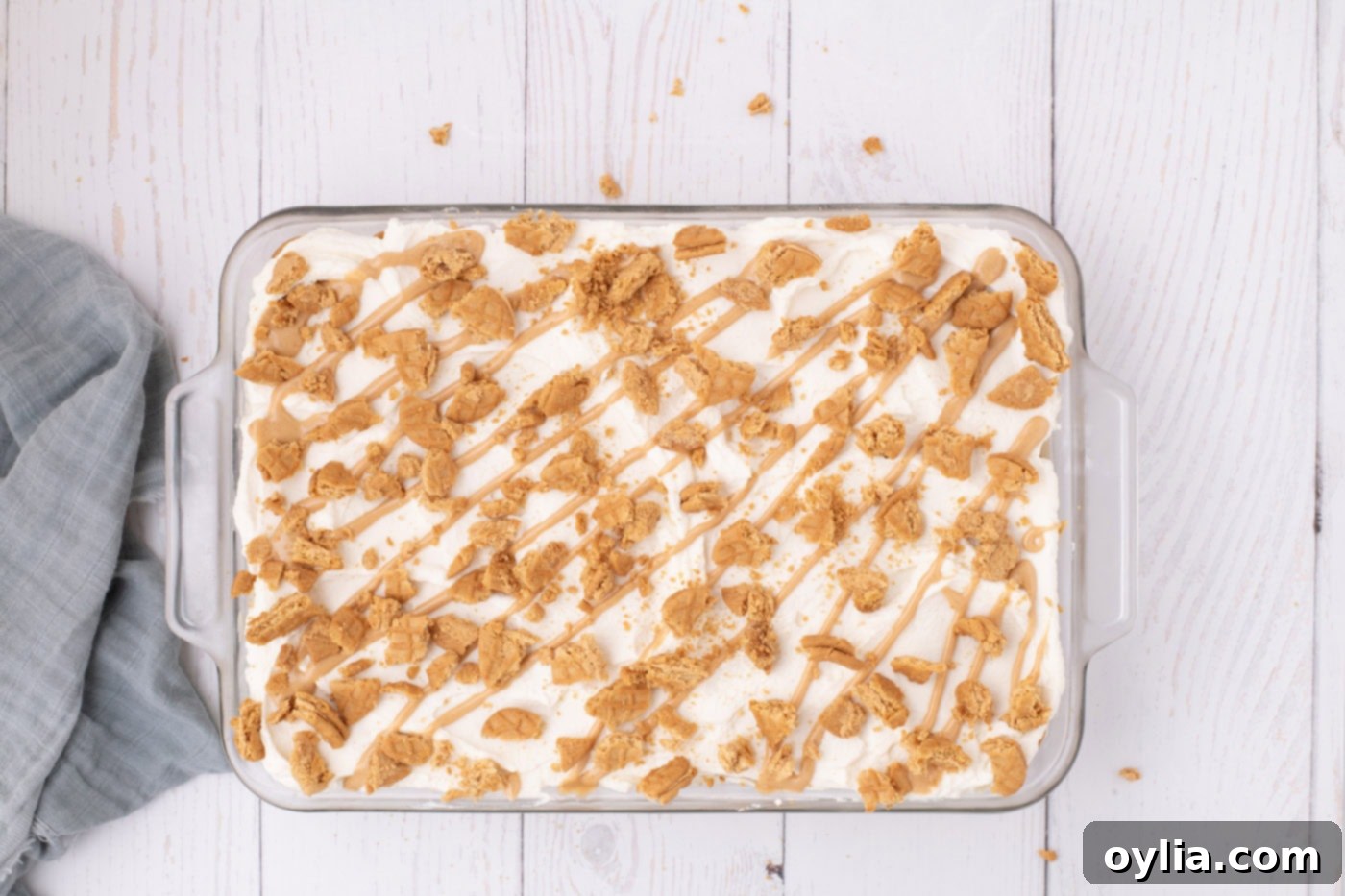 Nutter butter icebox cake in a dish with crushed cookies and peanut butter drizzle on top