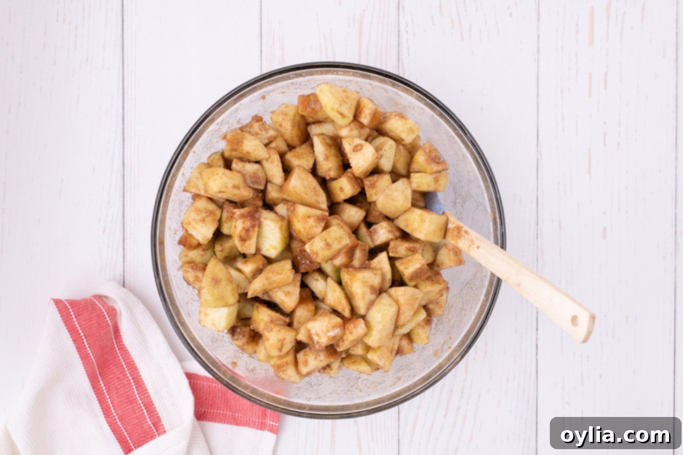 Chopped Granny Smith apples coated in a vibrant mix of sugar, flour, vanilla, lemon zest, cinnamon, nutmeg, and salt in a large mixing bowl, preparing for apple pie filling.