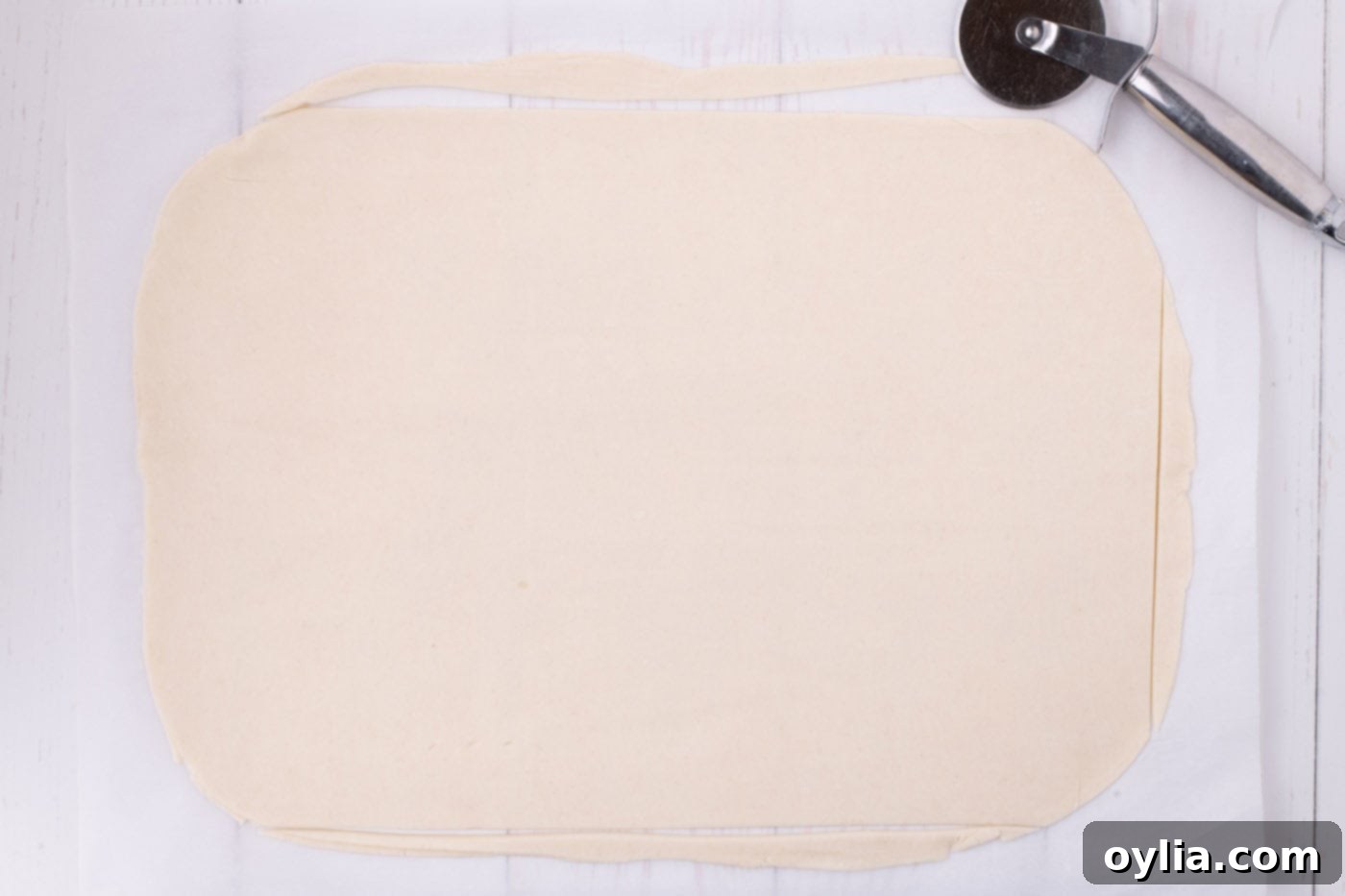 Two pie dough circles seamlessly rolled together and cut to the precise rectangular length for a jelly roll pan, forming the base of the slab pie.