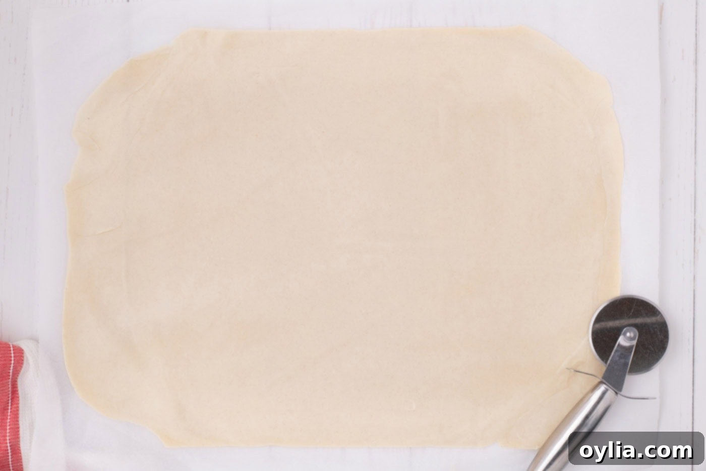 A neatly rolled-out rectangle of pie dough, perfectly shaped for the top crust of an apple slab pie, resting on a surface.