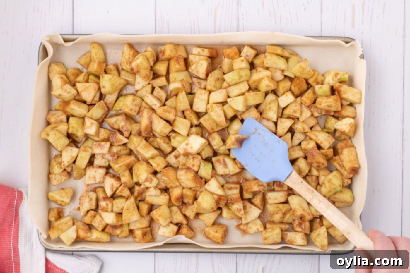 A generous layer of chopped, spiced apples distributed evenly over the pie dough base in a sheet pan, ready for the top crust.