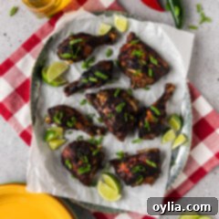 Jerk Chicken on a parchment lined serving tray with limes on the side