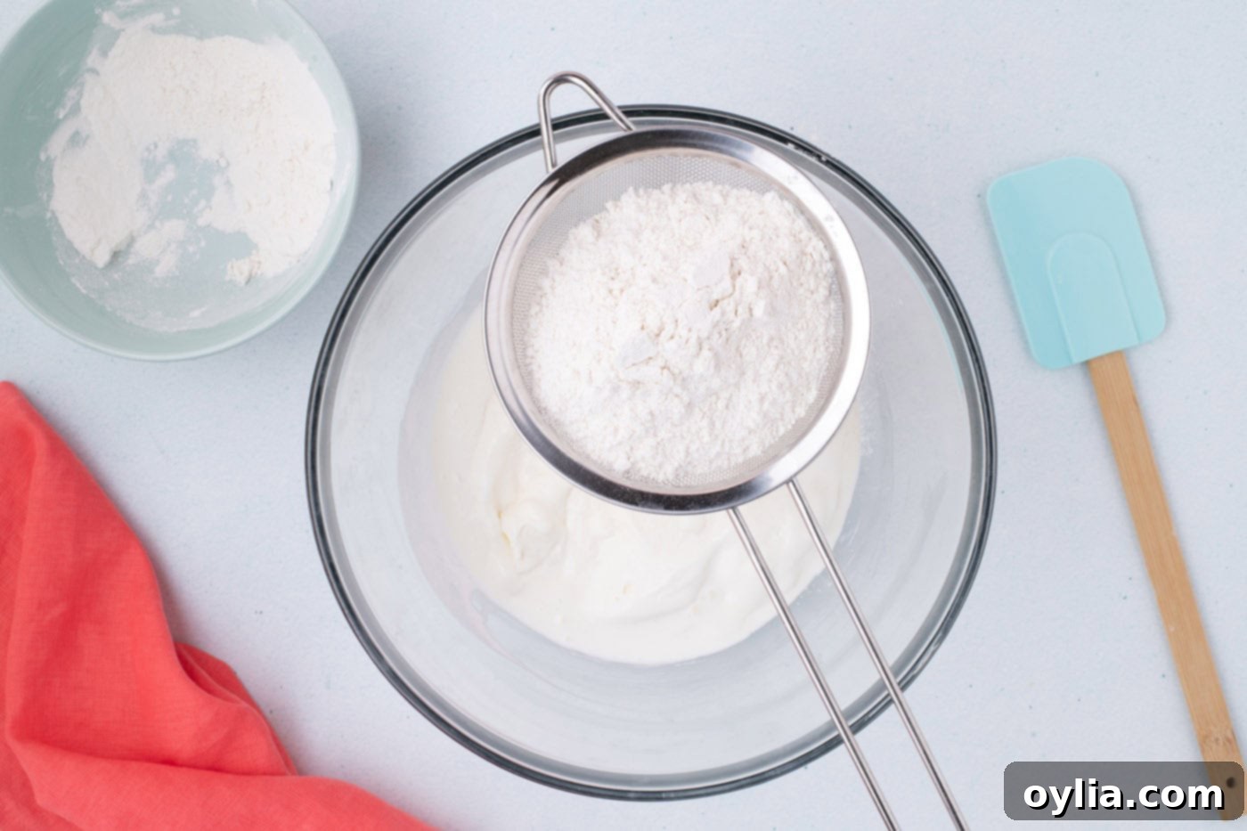 Sifting self-rising flour over melted vanilla ice cream in a bowl