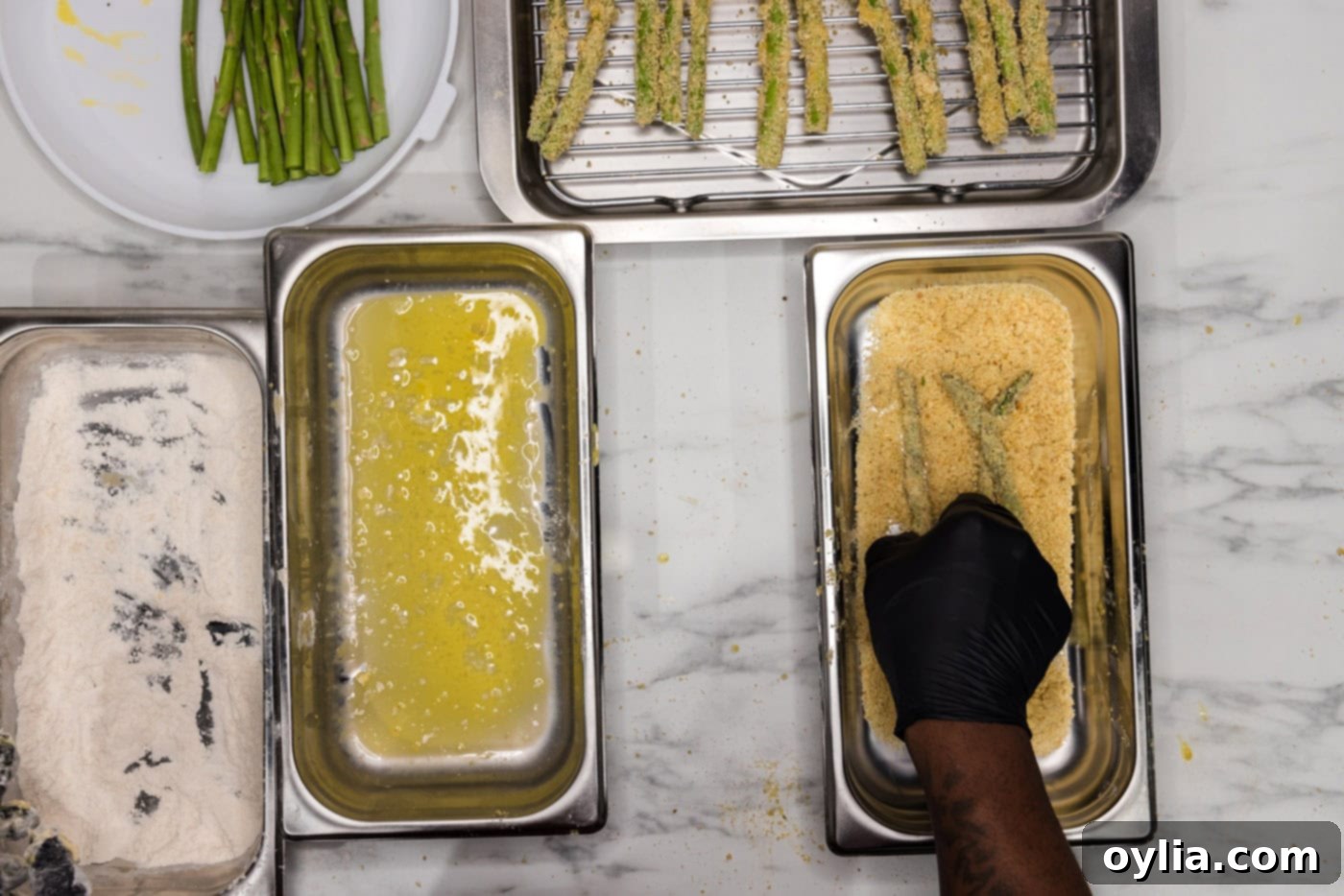 dredging asparagus spears in breadcrumb mixture
