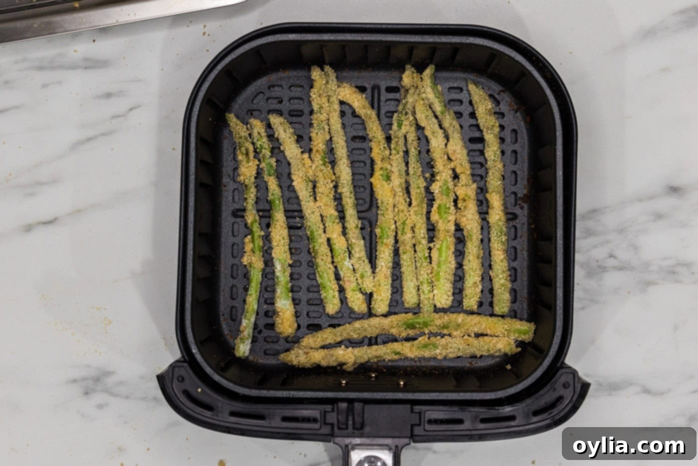 breaded asparagus fries in an air fryer basket