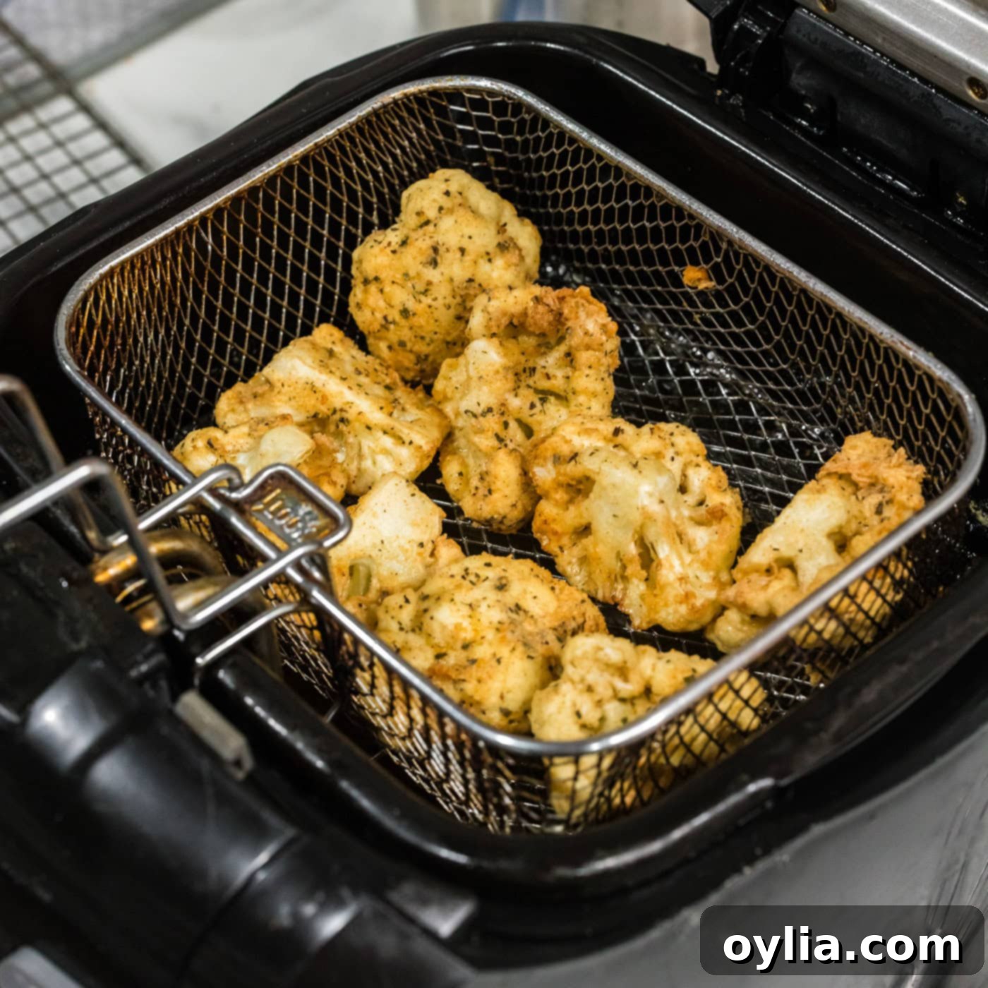 deep fried cauliflower florets in a fryer basket
