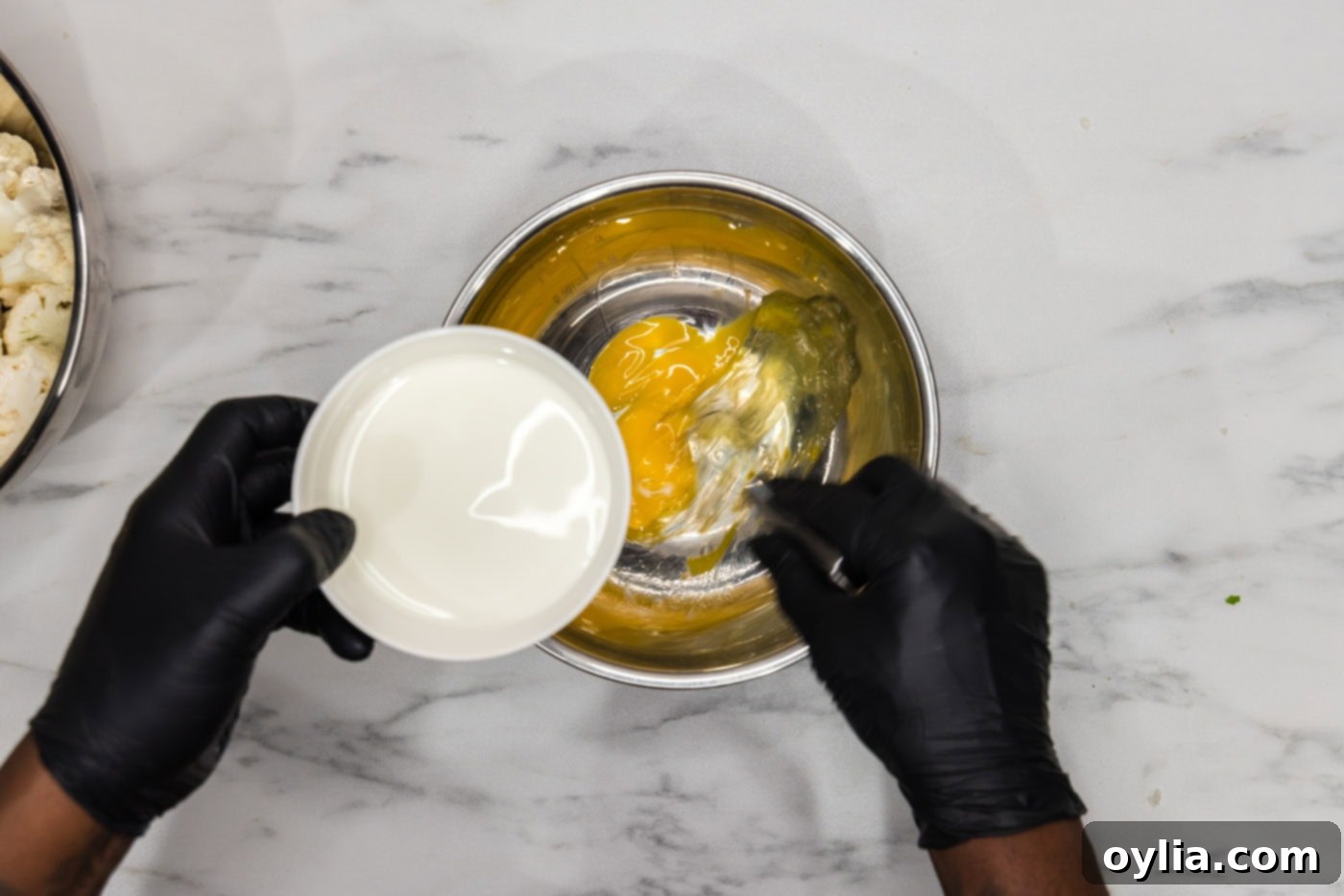 adding milk to whisked eggs in a bowl