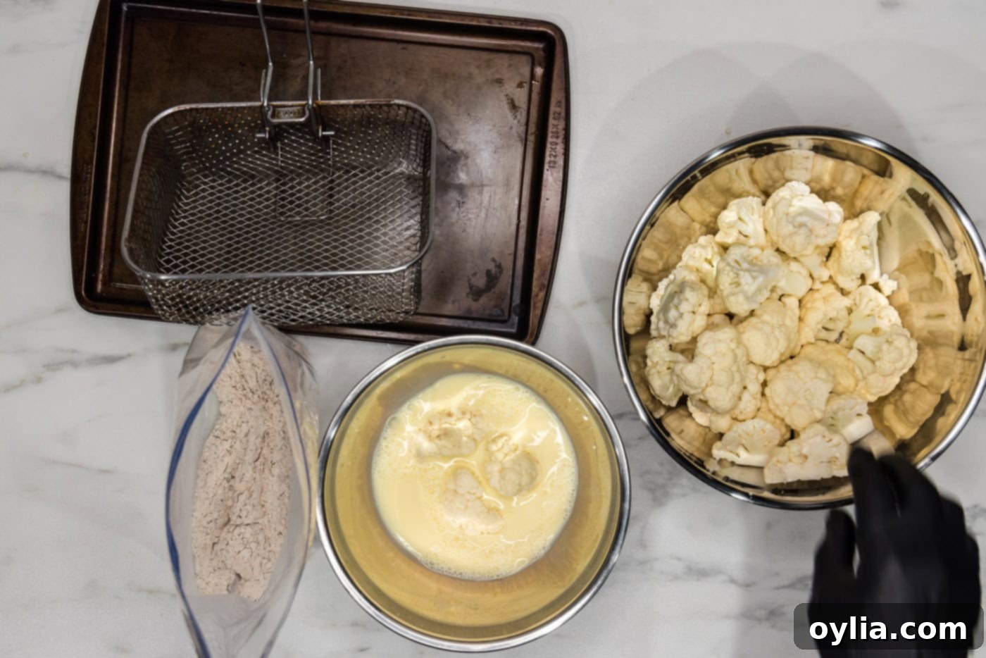 breaded cauliflower florets in a bowl of whisked eggs and milk