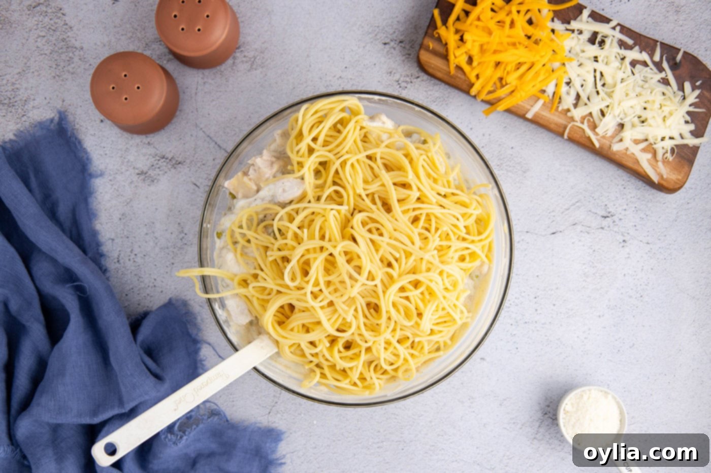 Turkey Tetrazzini 7 Spaghetti noodles being added to the creamy tetrazzini mixture in a large bowl, ready for mixing