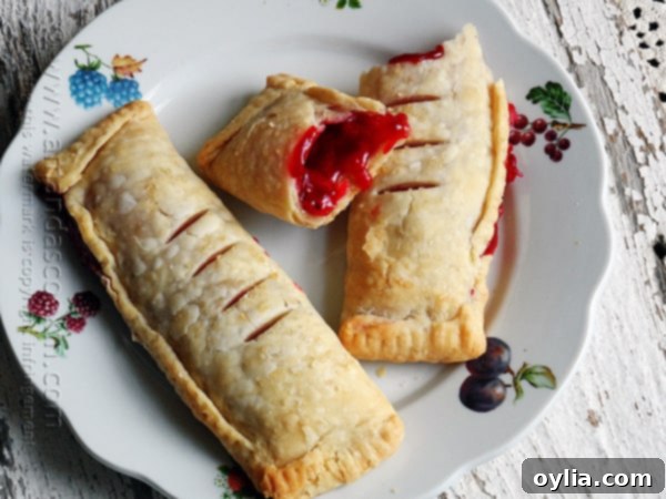 Two golden-brown cherry hand pies with crimped edges on a baking sheet