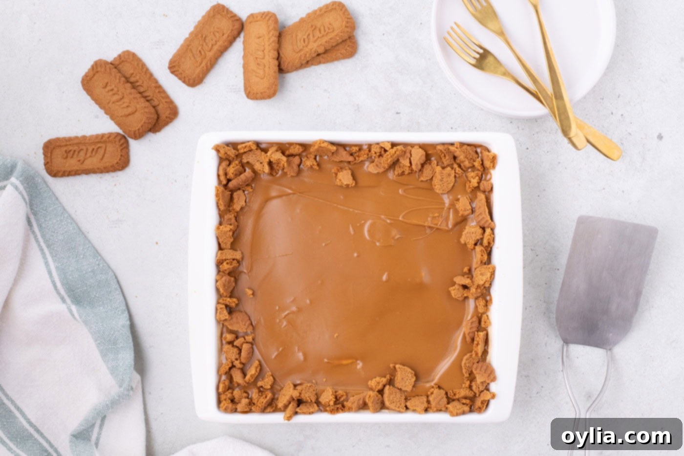 Biscoff icebox cake in a baking dish with cookie butter and crushed cookies as garnish