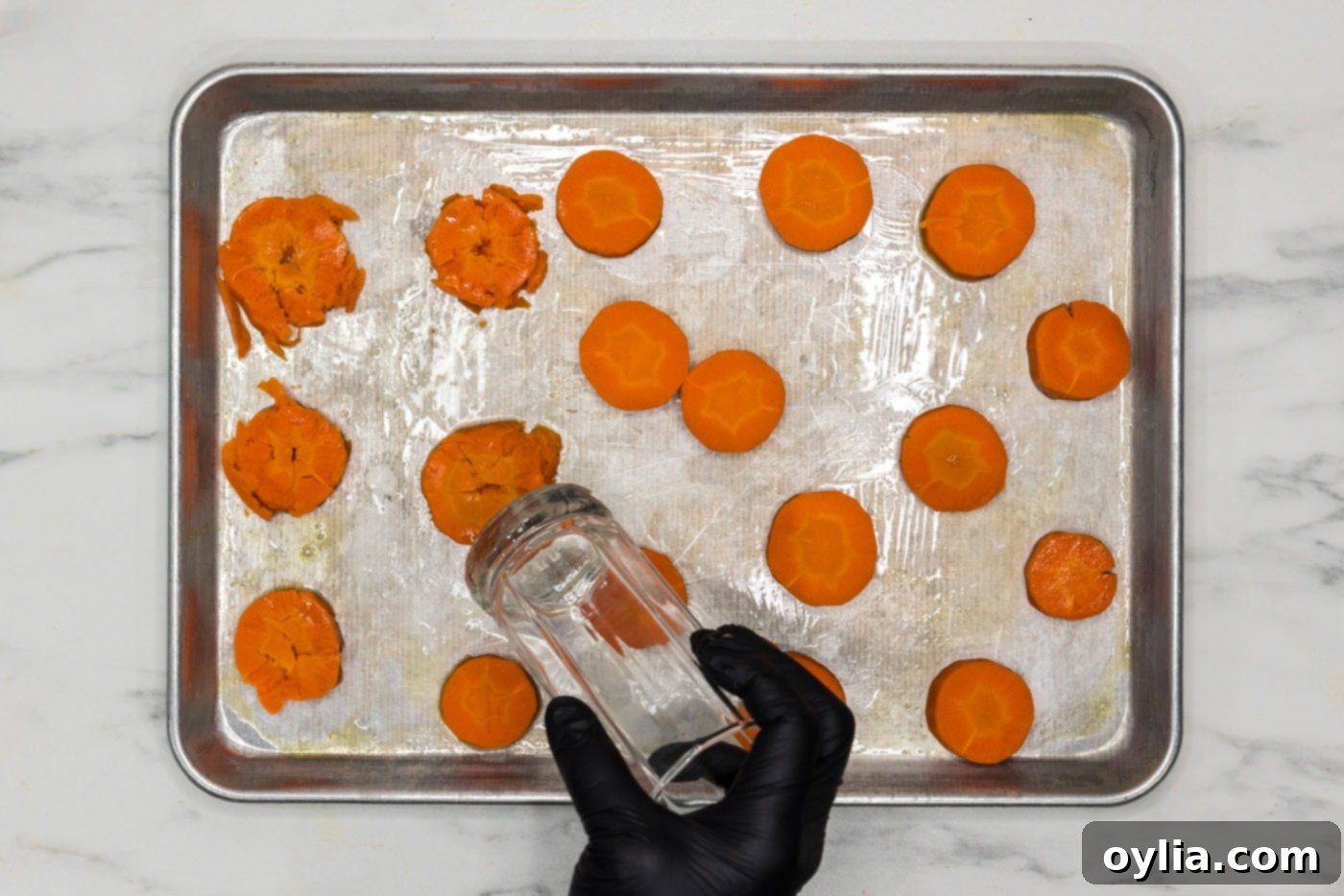 smashed carrots on a baking sheet with the flat end of a drinking glass