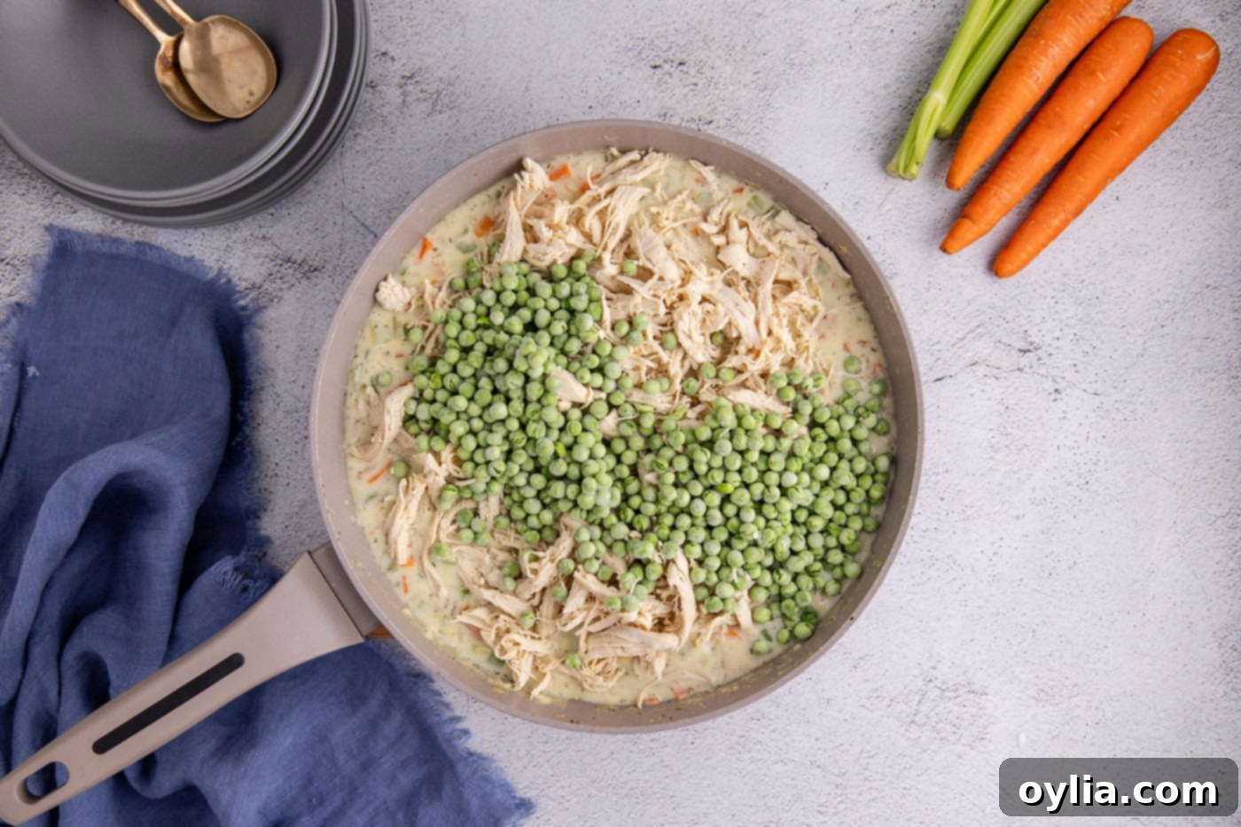 frozen peas added to chicken pot pie mixture in a skillet