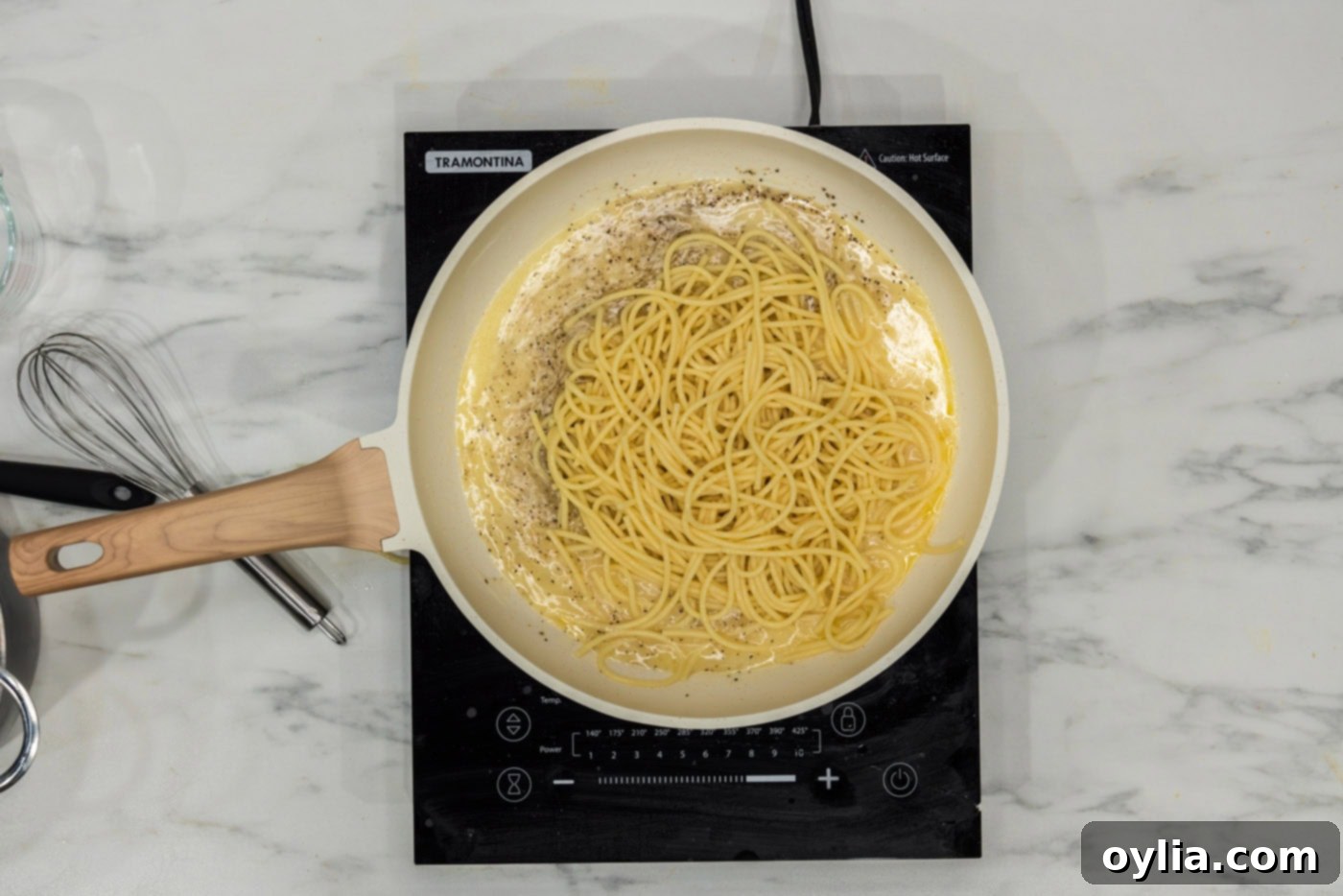 adding cooked spaghetti to a skillet with garlic and butter sauce, ready to be coated