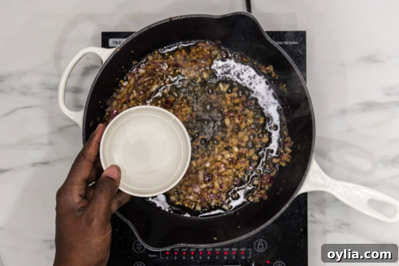adding water to skillet with sauteed onion and garlic