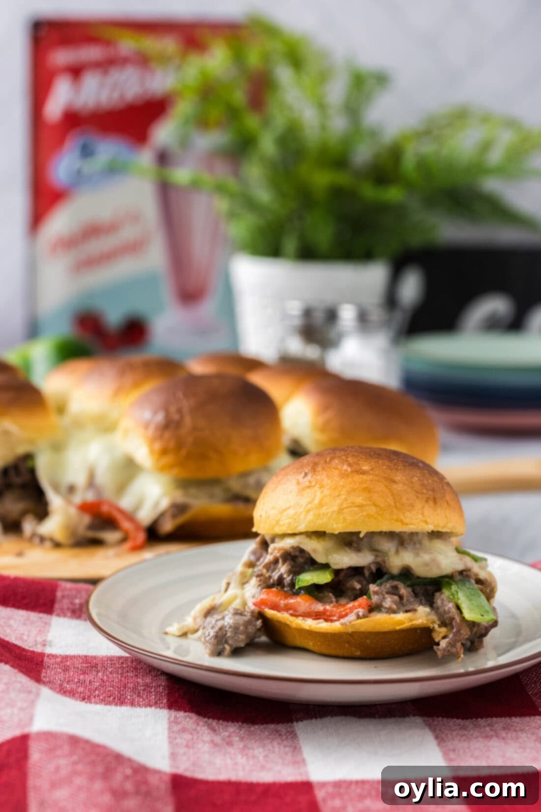 Philly Cheesesteak Slider on a plate with more Philly Cheesesteak Sliders in the background