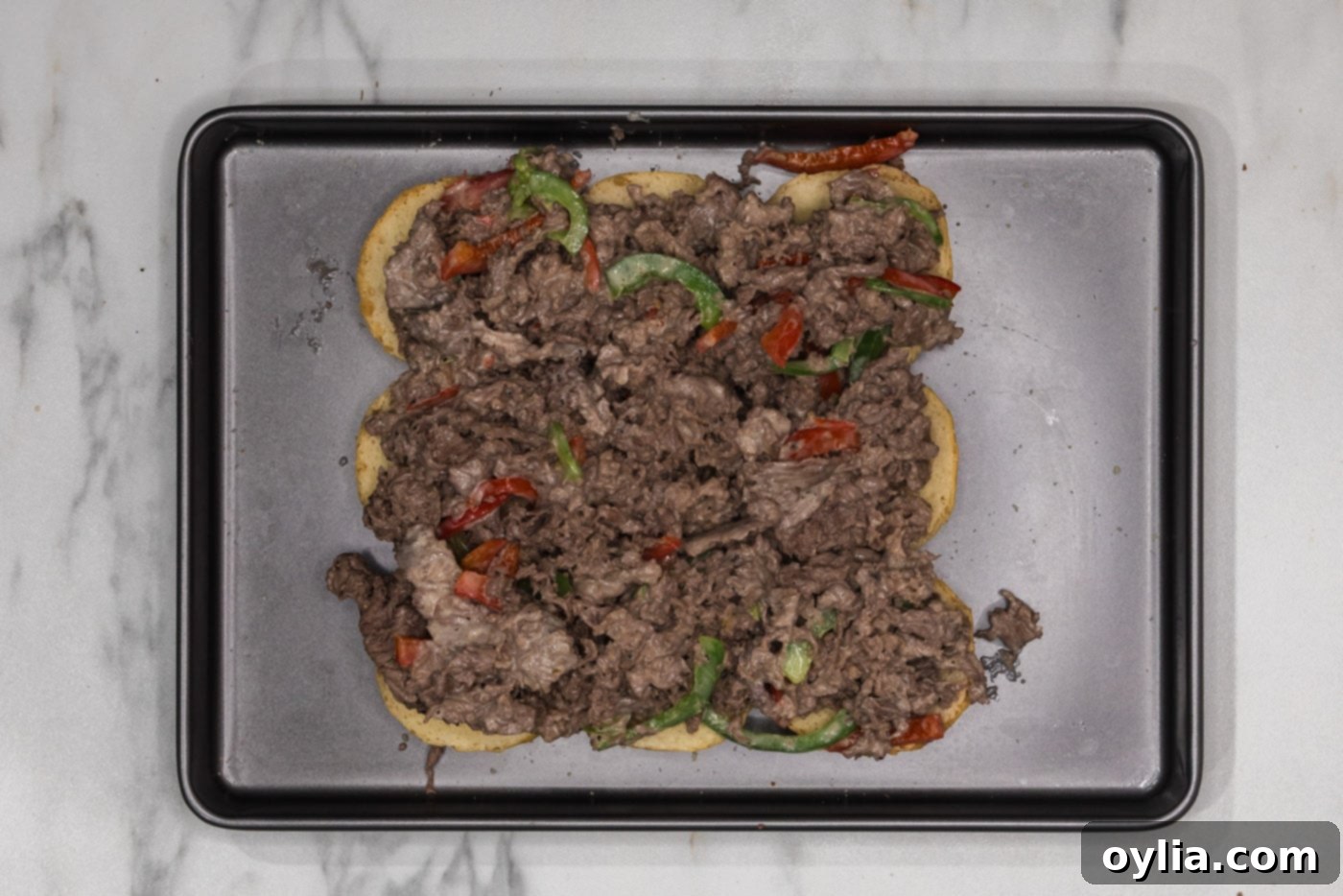 shaved beef and bell pepper mixture on top of slider buns