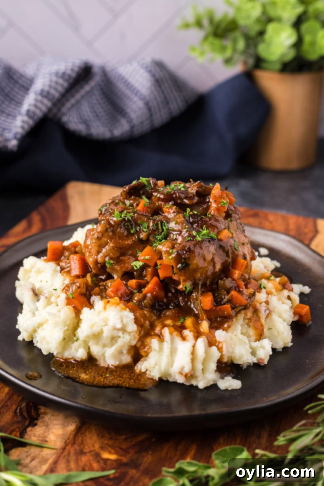 Tender Slow Braised Oxtail 3 Braised Oxtail served over mashed potatoes on a plate, garnished with fresh herbs.