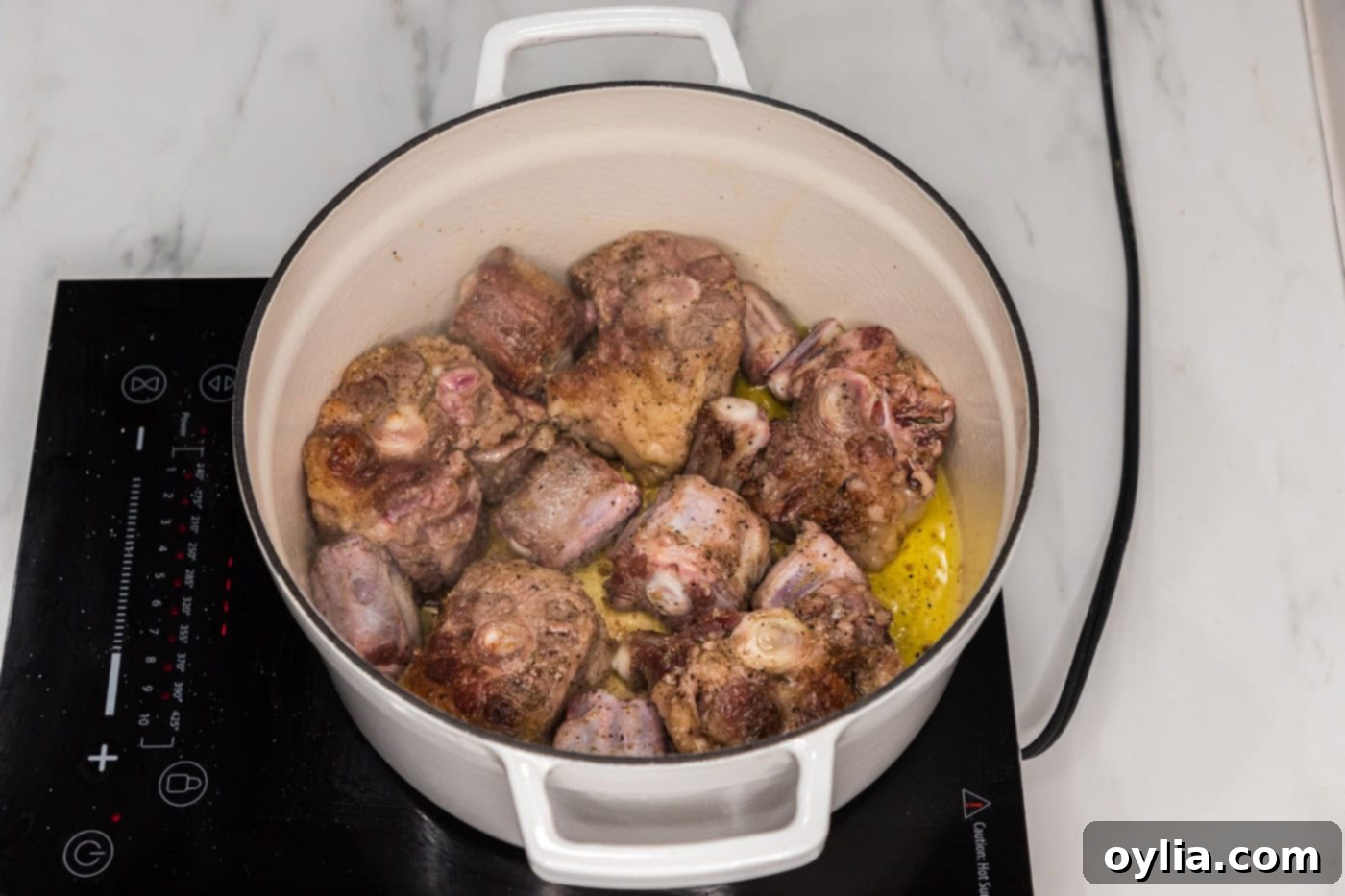 browned oxtail in a dutch oven before braising, showing a rich, dark crust.