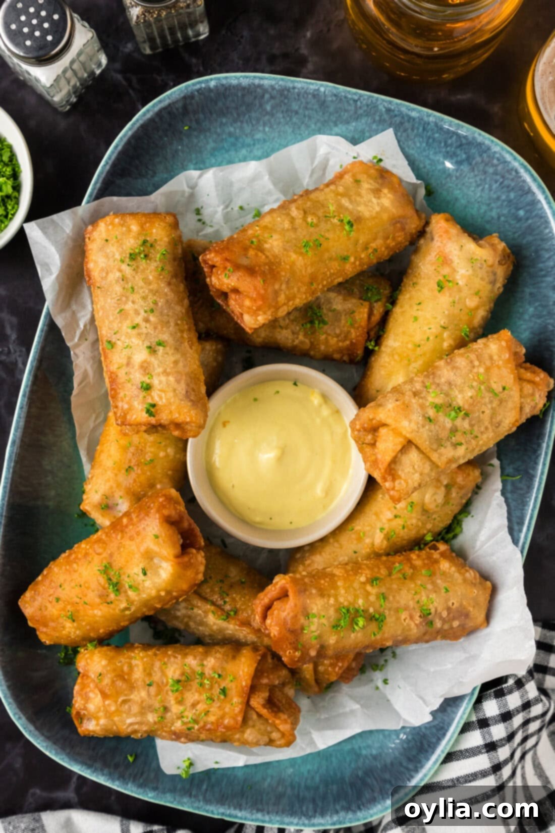Corned Beef Egg Rolls on a blue platter with a bowl of dipping sauce in the middle