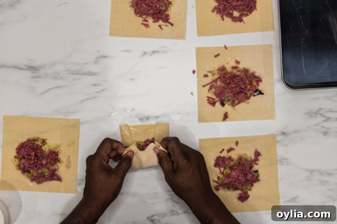 hands folding egg roll wrappers