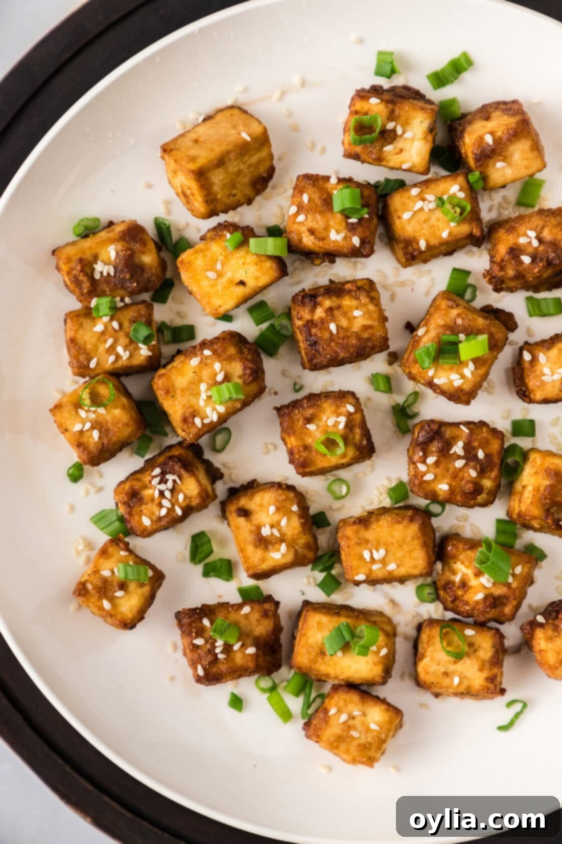 Close up photo of a plate of perfectly crispy and flavorful Air Fryer Tofu, garnished and ready to eat.