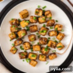Plate of Air Fryer Tofu garnished with sesame seeds and green onions.