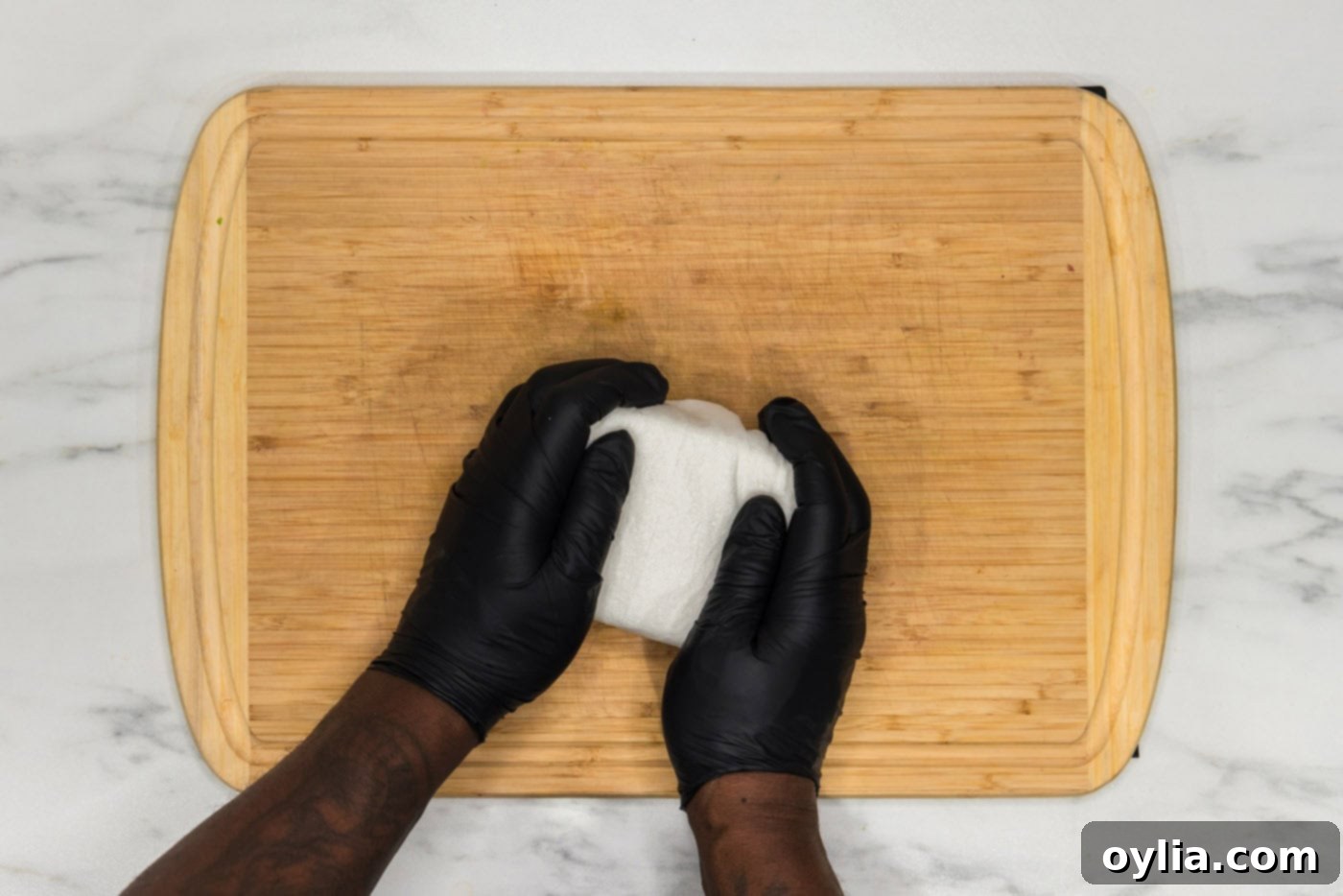 Hands gently squeezing excess moisture out of a block of tofu wrapped in paper towels.