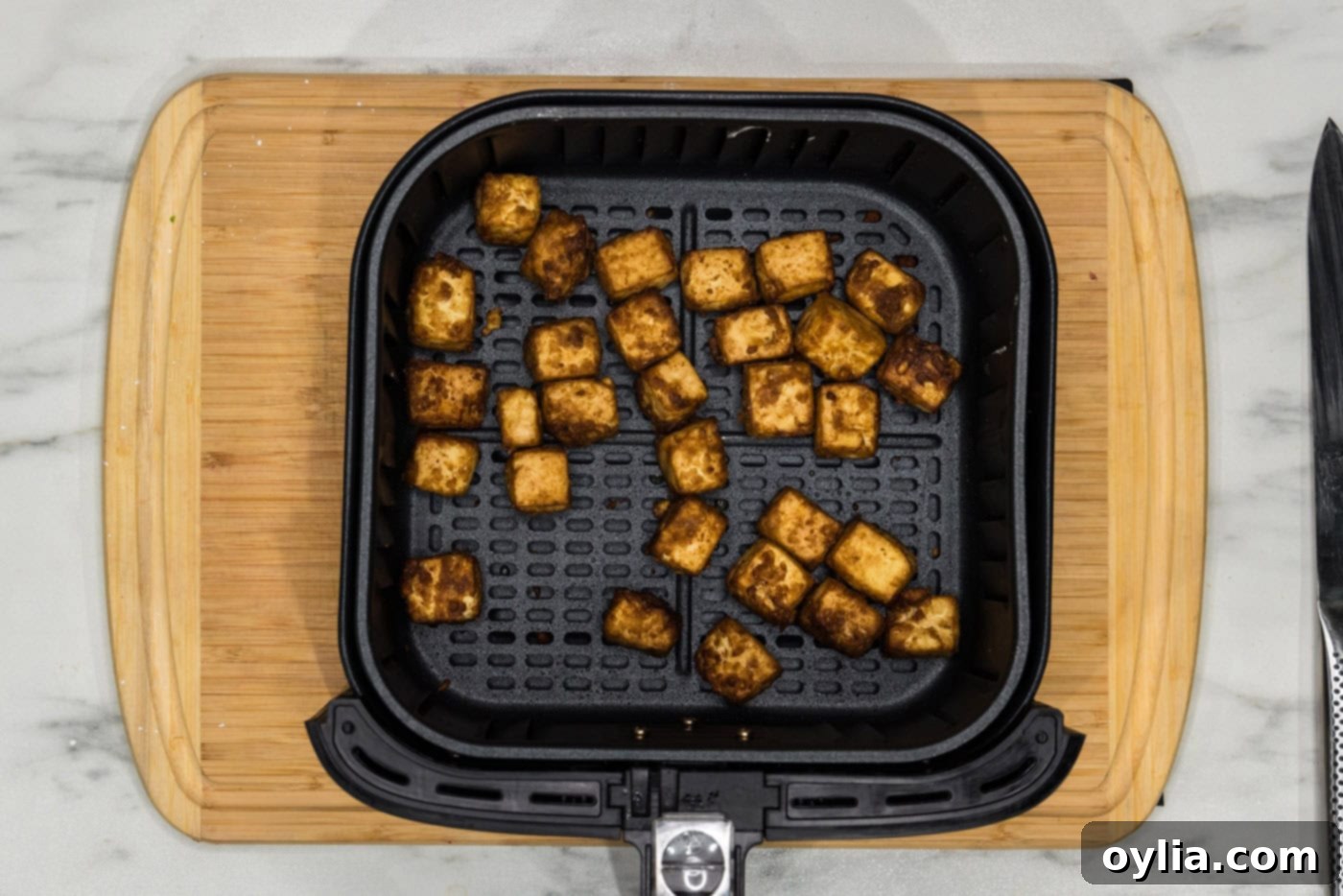Golden, crispy air-fried tofu pieces in an air fryer basket after cooking.