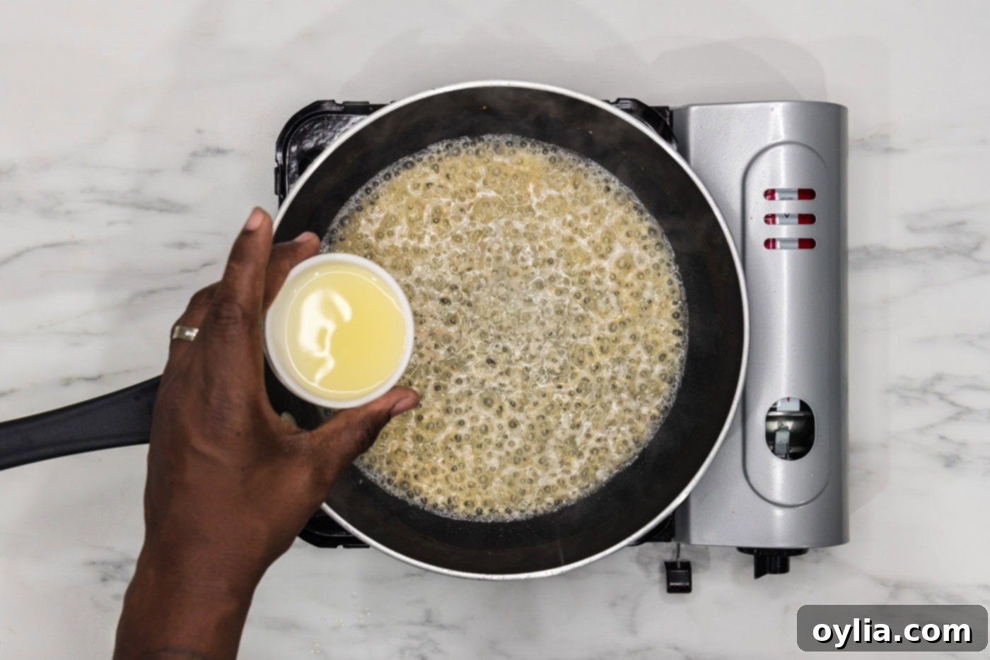 pouring lemon juice into skillet of white wine, shallots, and garlic