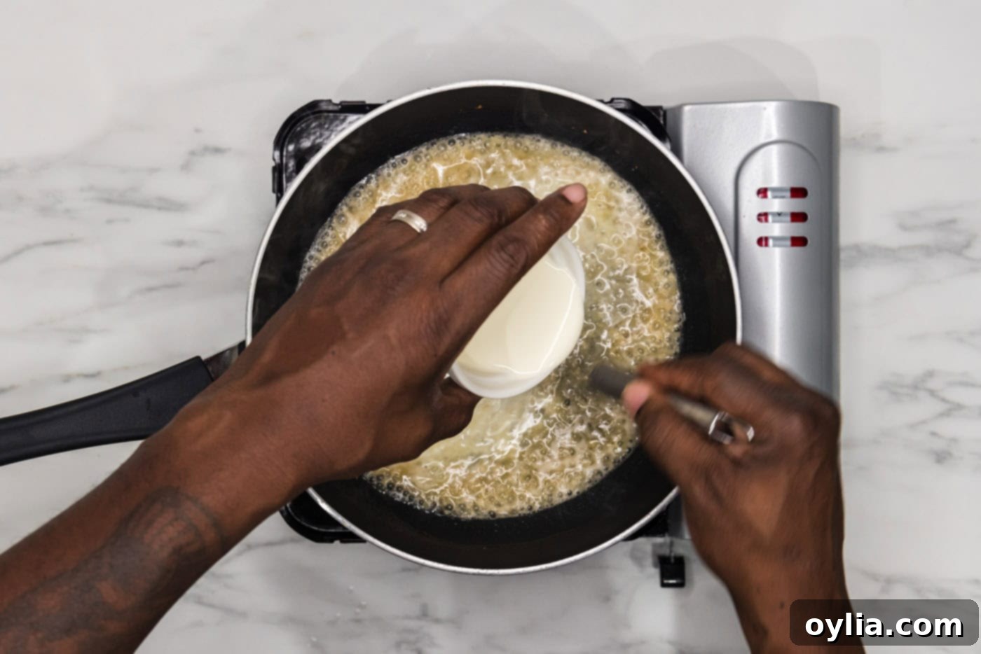 whisking heavy whipping cream into sauce in a skillet