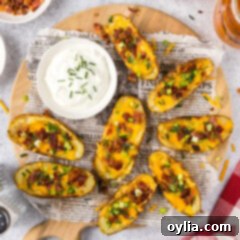 Potato Skins on a parchment lined wooden platter with a bowl of sour cream