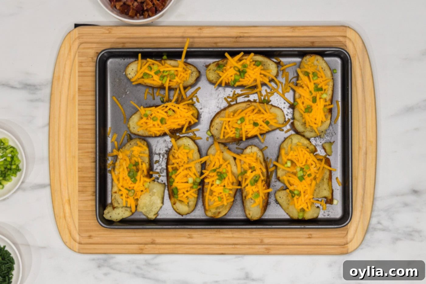 shredded cheese, green onions, and chives on top of potato skins