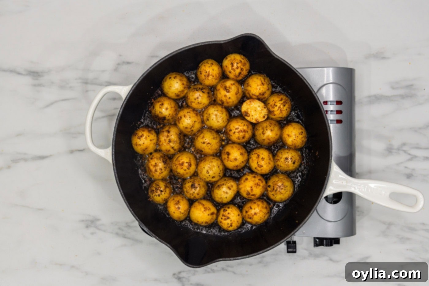baby potatoes, skin side up, cooking in a skillet