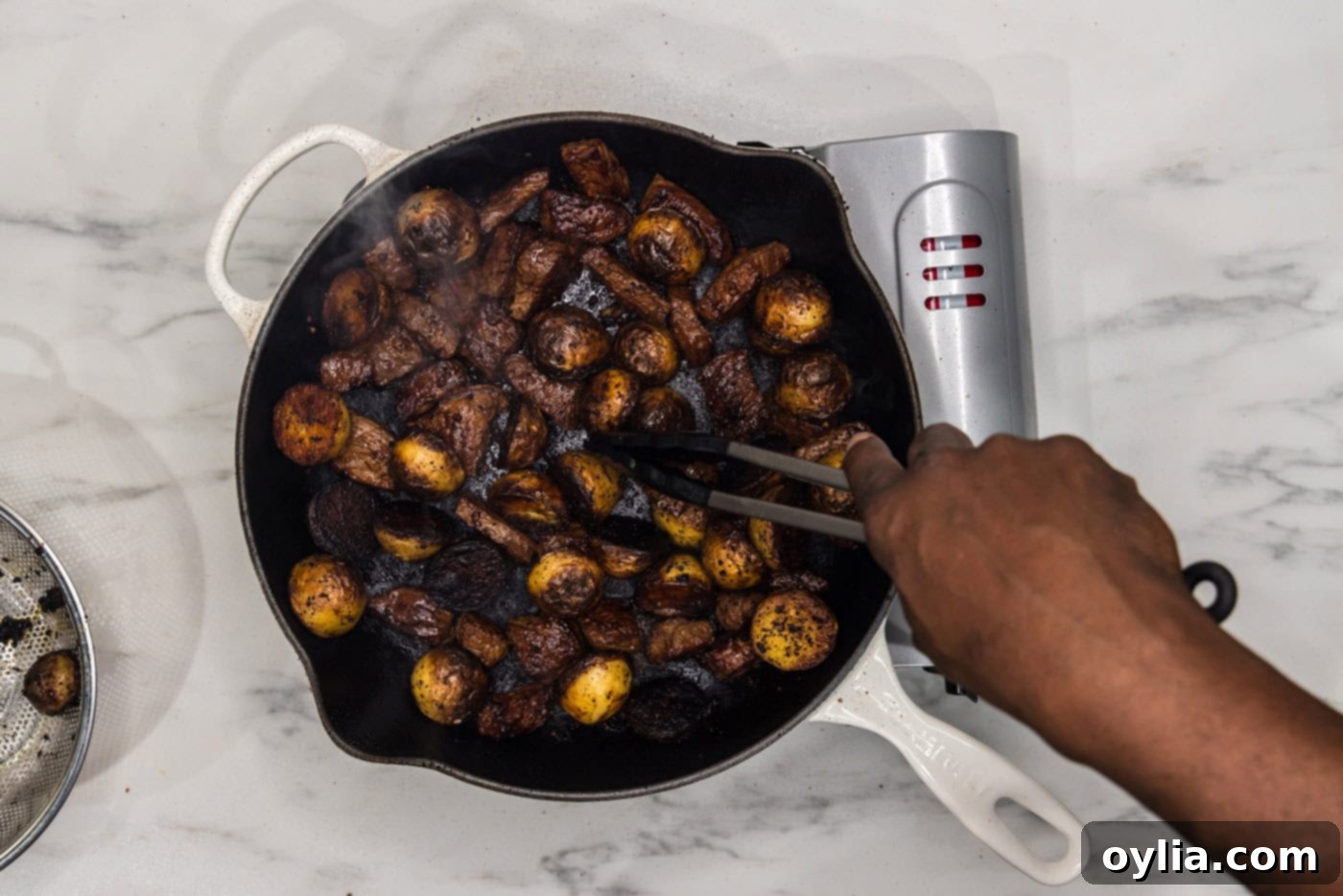 steak and potatoes cooking in a skillet