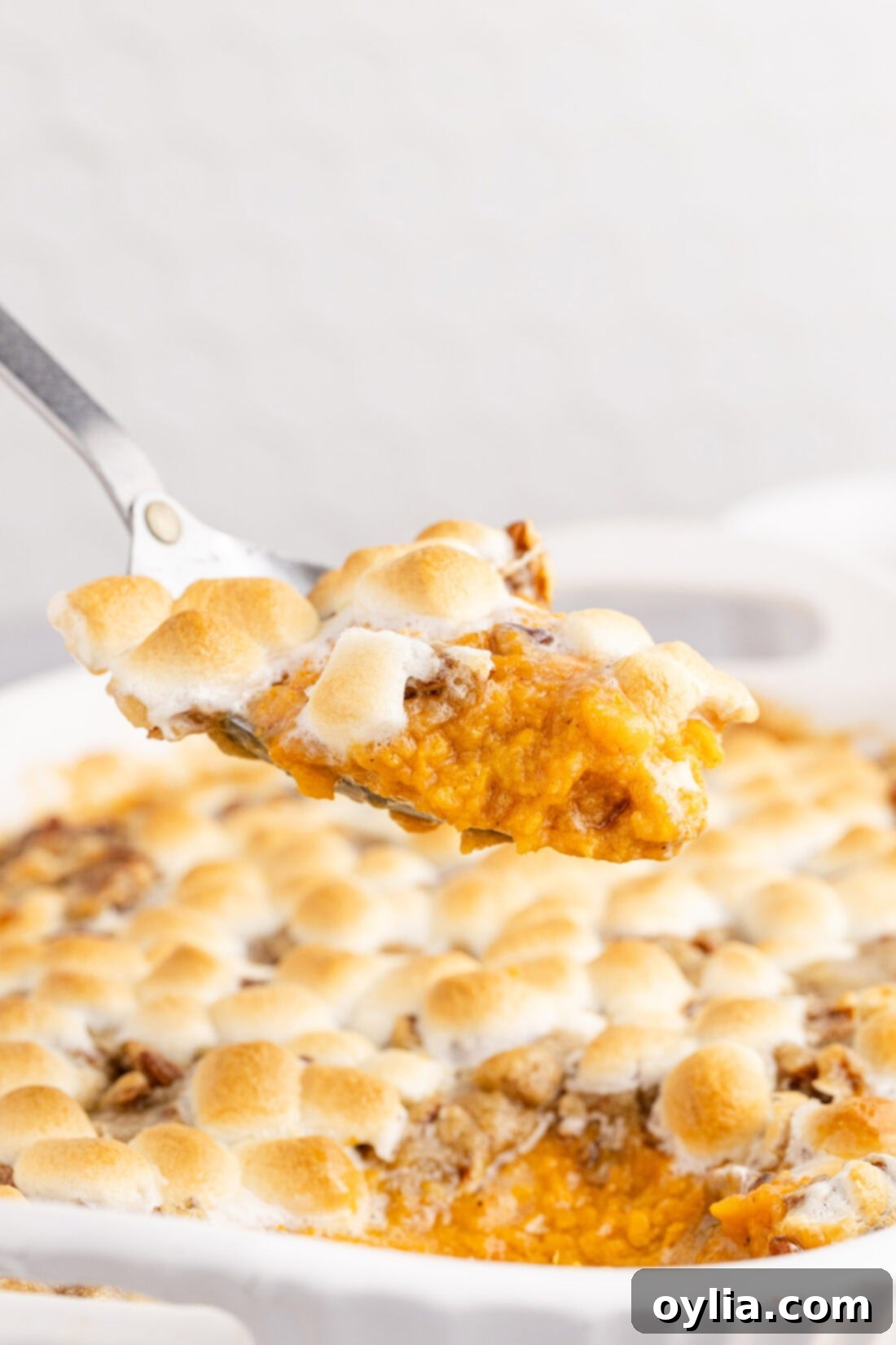 Spoonful of Sweet Potato Casserole held above the Sweet Potato Casserole
