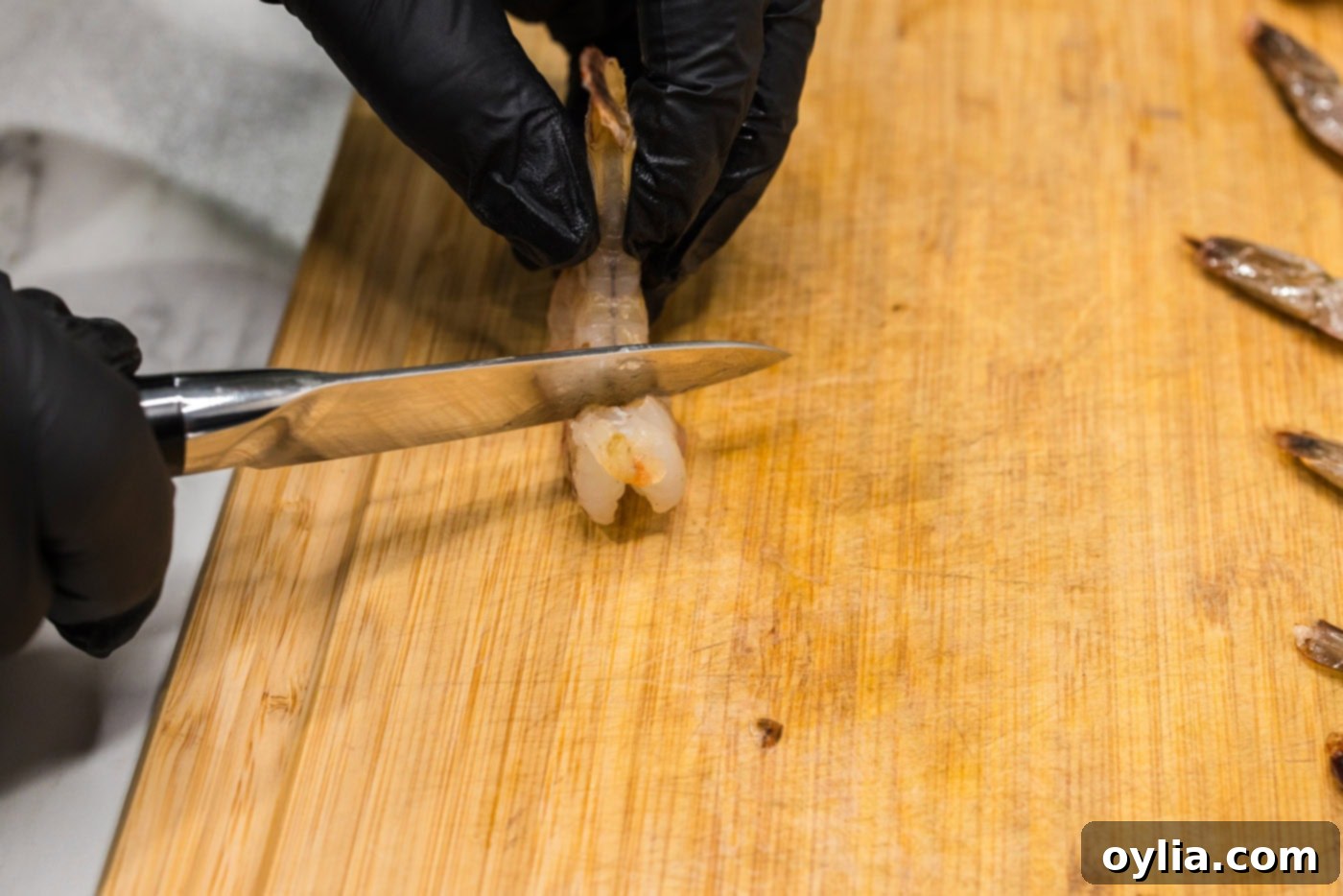 scoring shrimp with a knife on a cutting board