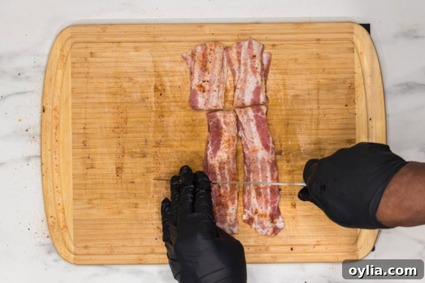 slicing bacon into thirds on a cutting board