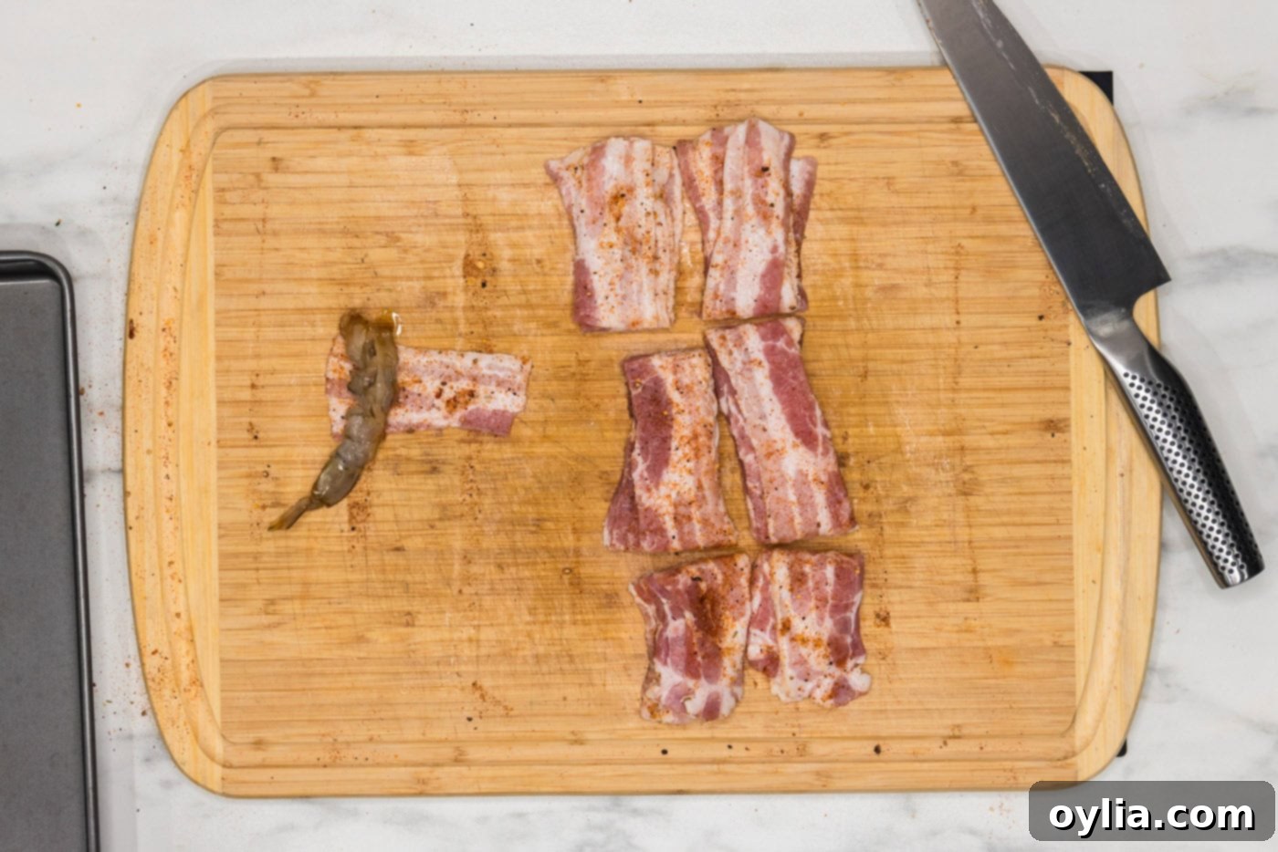 wrapping shrimp in bacon on a cutting board