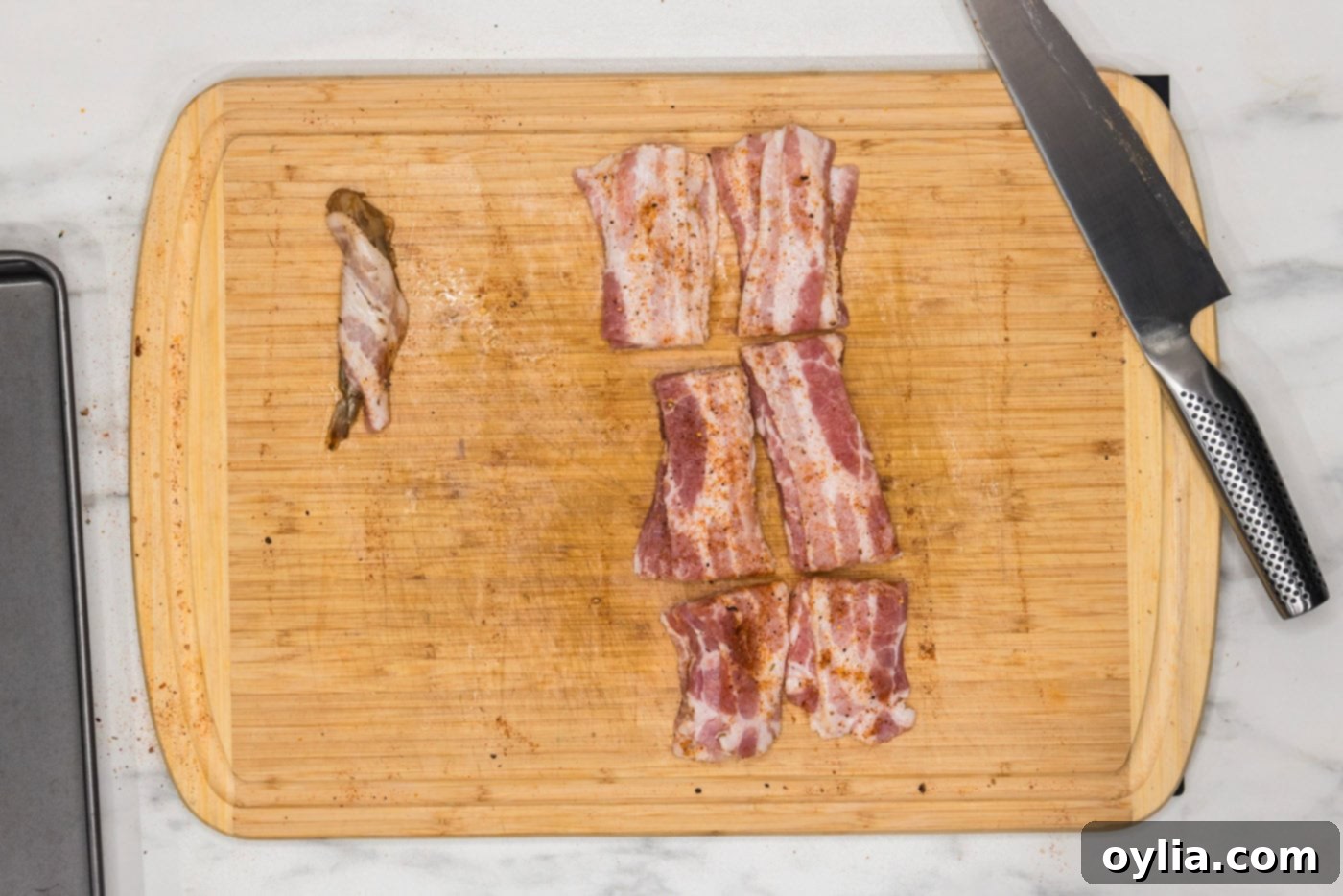 bacon wrapped shrimp next to bacon slices on a cutting board