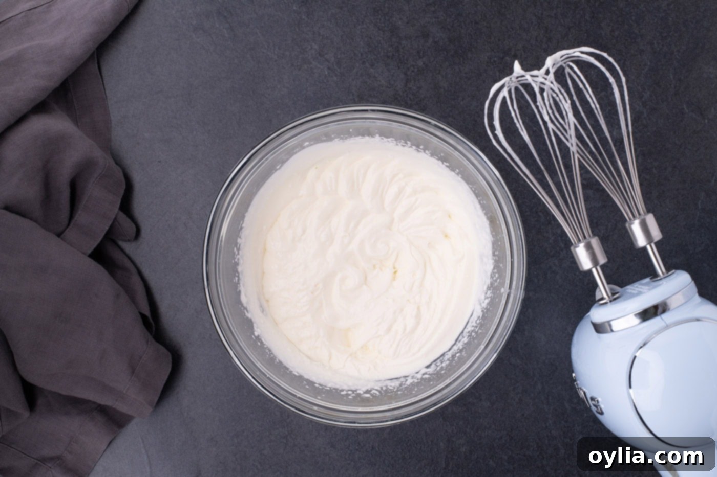 Homemade whipped cream in a bowl with a hand mixer, forming soft peaks