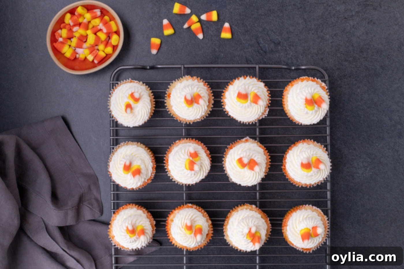 Whipped cream and candy corn adorning mini candy corn cheesecakes on a wire cooling rack