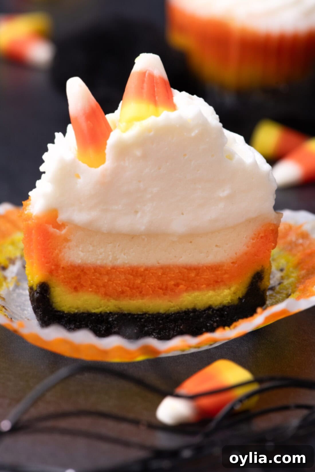 A mini candy corn cheesecake cut in half, revealing the perfect layers of yellow, orange, and white