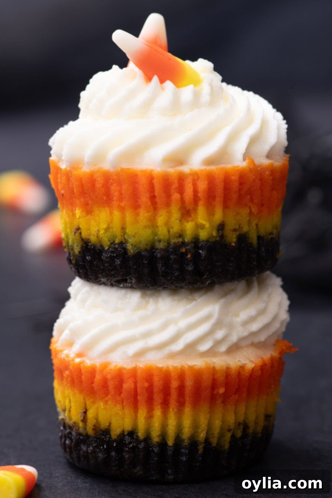 Two Mini Candy Corn Cheesecakes stacked on top of each other, showcasing the colorful layers